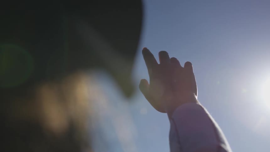 A hand is held up toward the sky