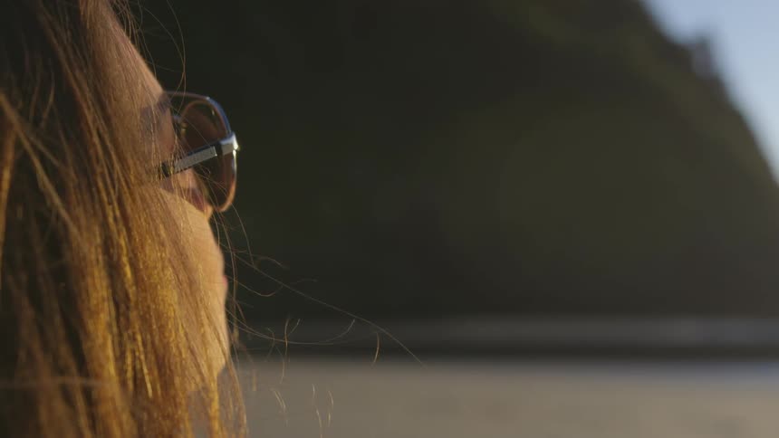 A woman in sunglasses standing at the beach
