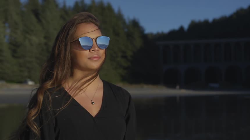 A woman with sunglasses standing by the lake