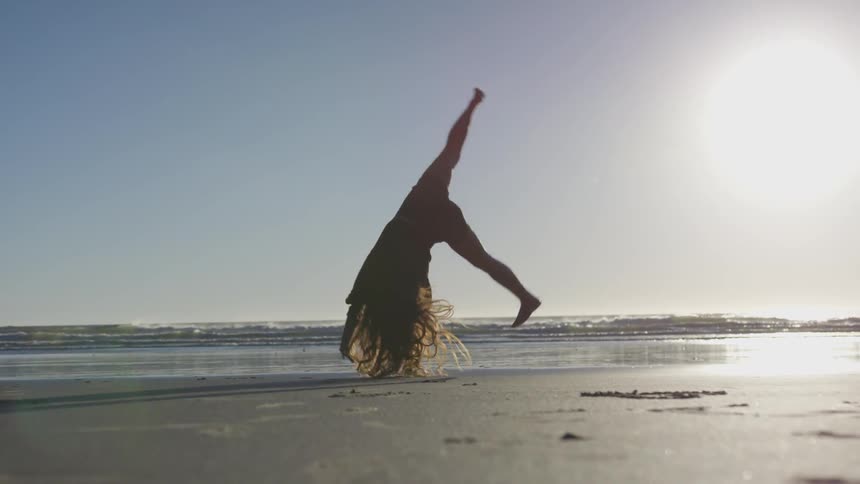 Girl doing cartwheel on beach