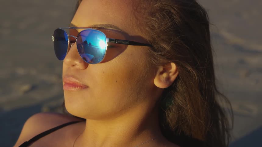 Woman wearing sunglasses lays on the beach