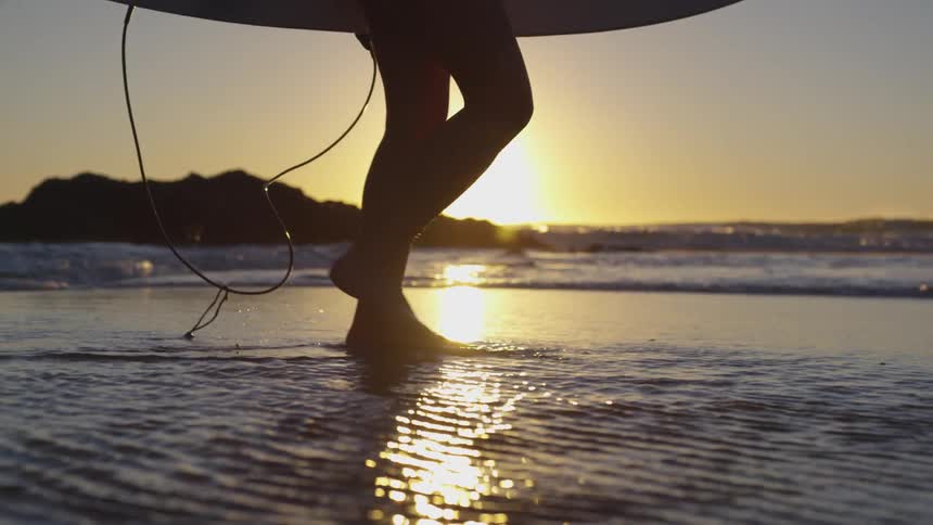 A person is walking on a beach at sunset