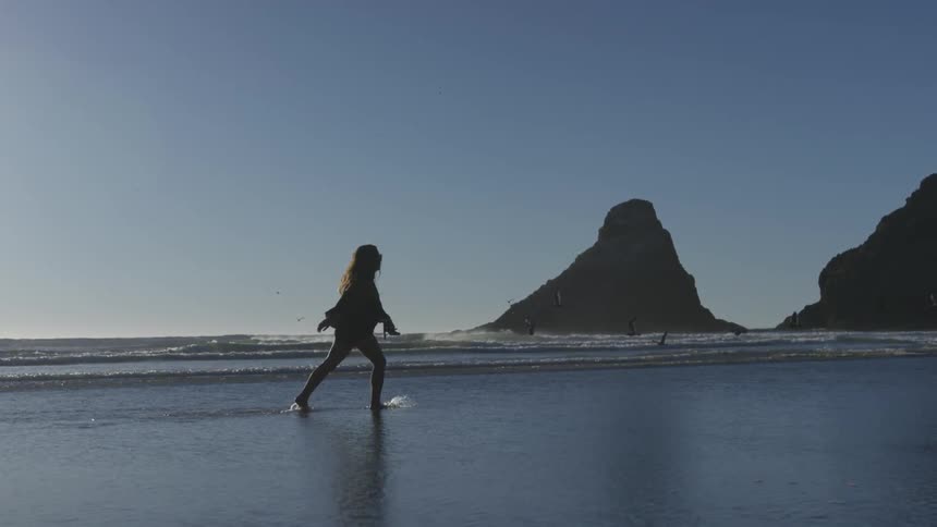 Woman running and splashing on the coast of a beach on a sunny day