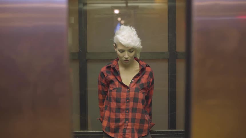 A woman is looking down at her feet while the doors of an elevator close