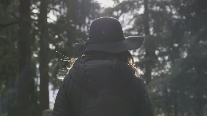 Woman wearing a brimmed hat walks in the forest