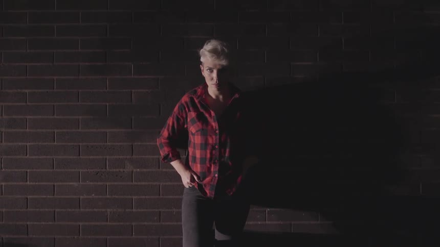 A woman leaning against a brick wall