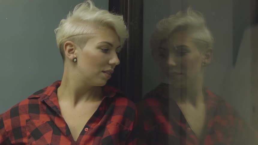 A woman staring at her reflection in a glass elevator