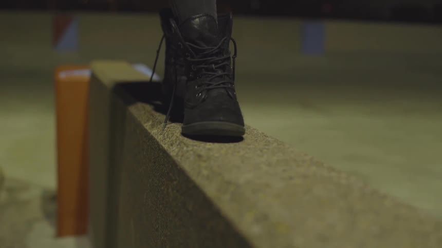 Somebody is walking on the wall in boots with their shoes untied like they are walking on a wire in the circus
