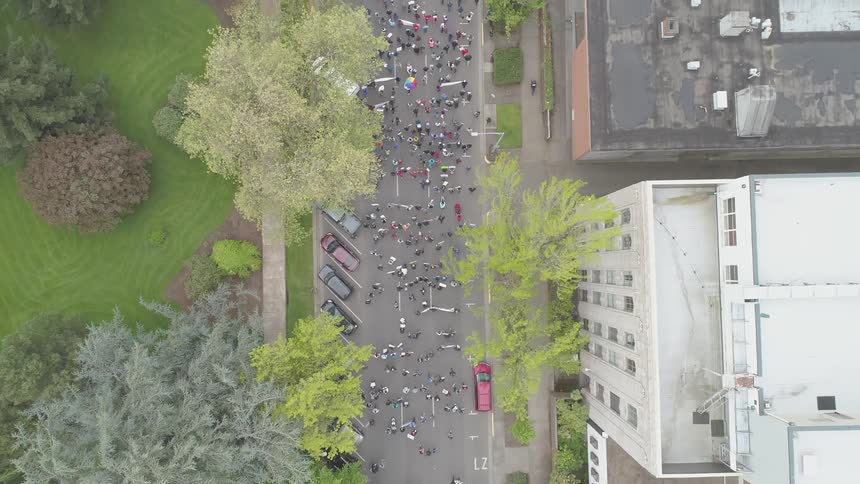 A parade of people carrying banners marches down a city road