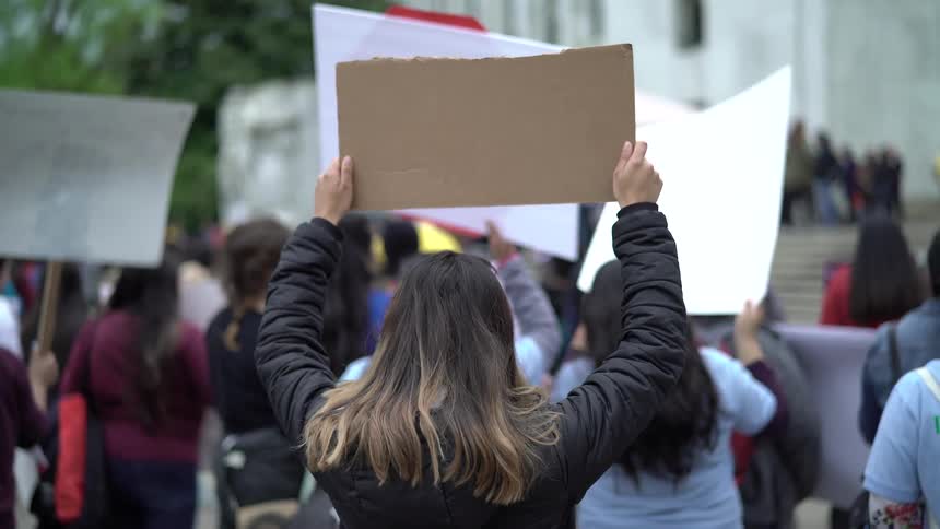 People hold placards and protest in the square by day