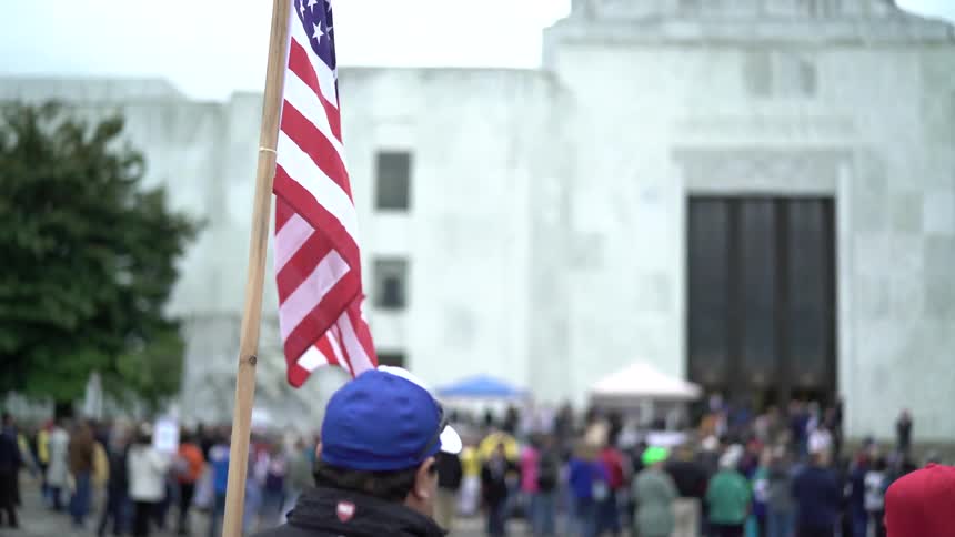 Man holding the us flag on a demonstration on the street