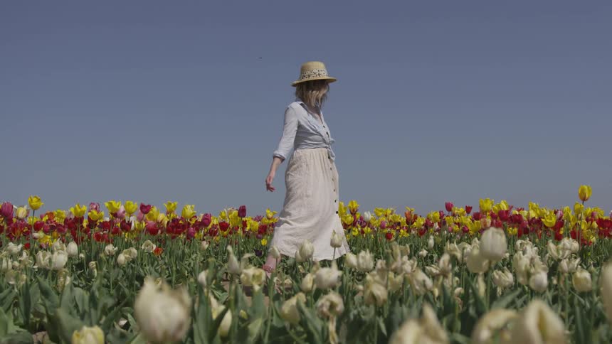 A woman is walking in a grass area with flowers