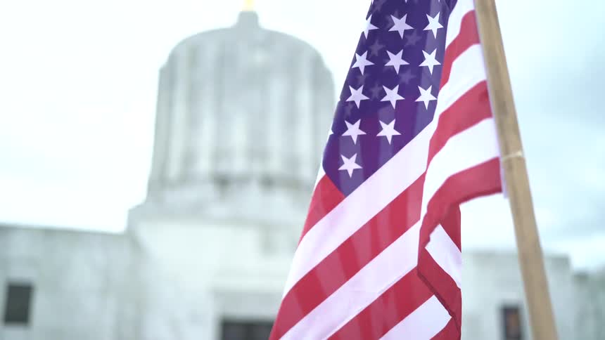 A united states flag waving in the wind in front of a government building