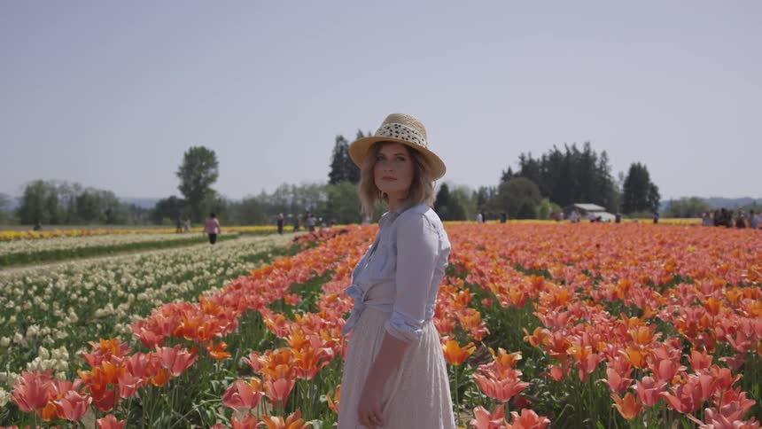 White woman standing in the middle of a flower field for a photoshoot