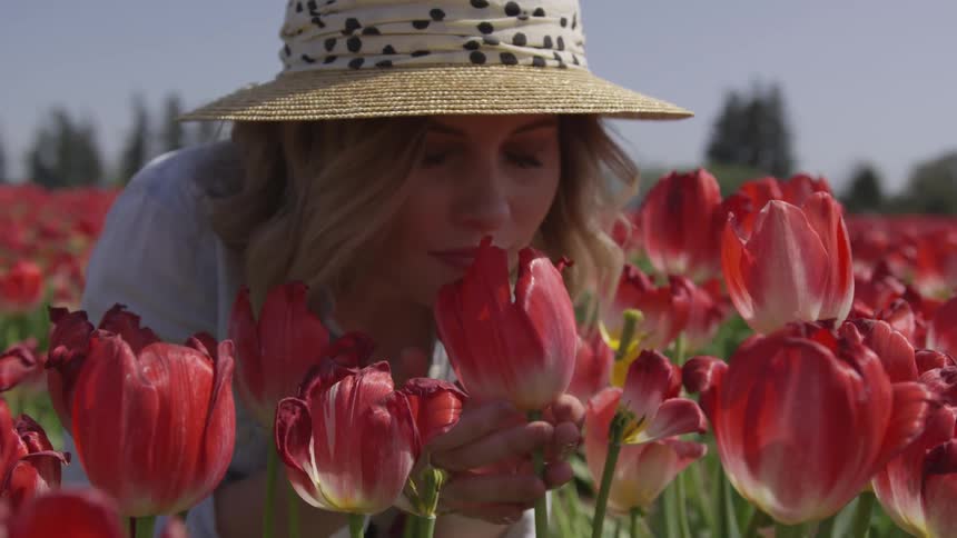 A woman is smelling flowers in a garden
