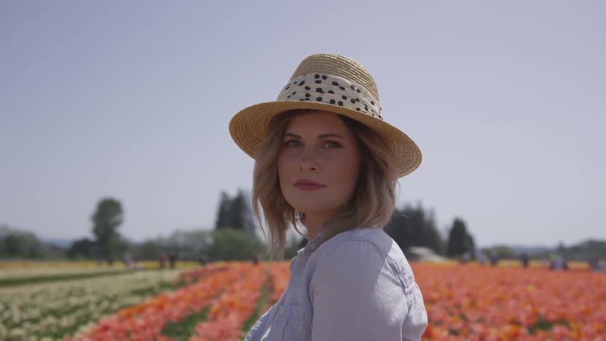 A woman looks over her shoulder as she stands in a field of cultivated flowers