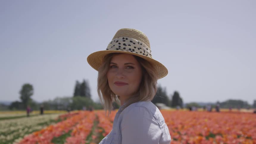 Woman in a straw hat standing in a flower field in the countryside