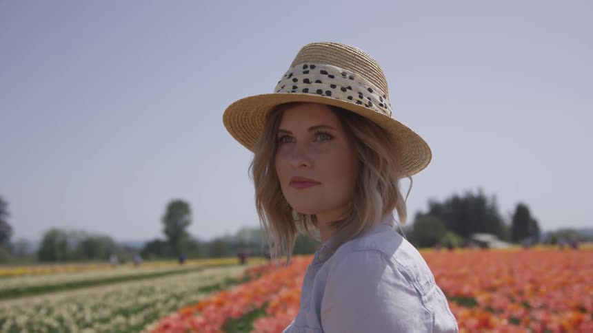 White woman wearing a hat posing for photo shoot in the middle of a flower field