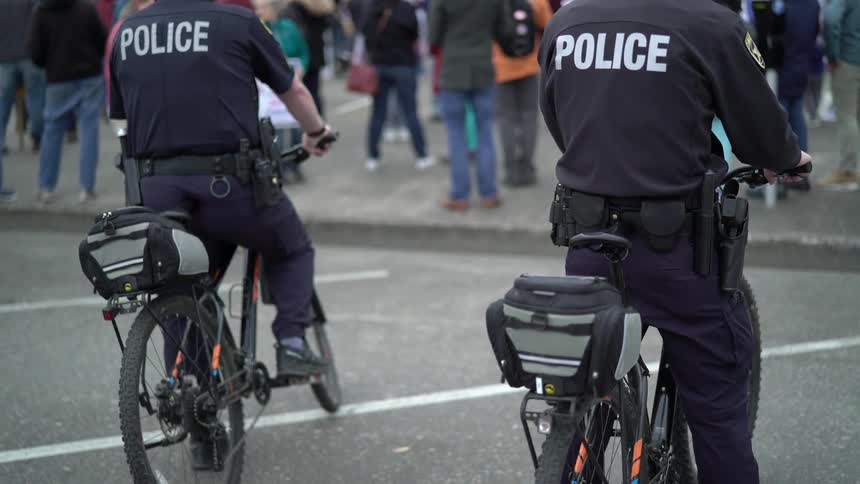 Two policemen on bikes watch the protesters in the daytime