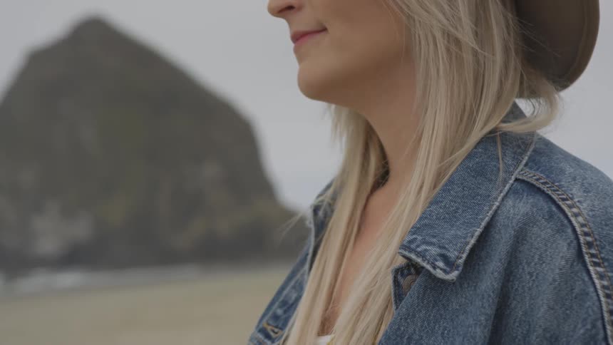 A woman is outdoors by the beach smiling