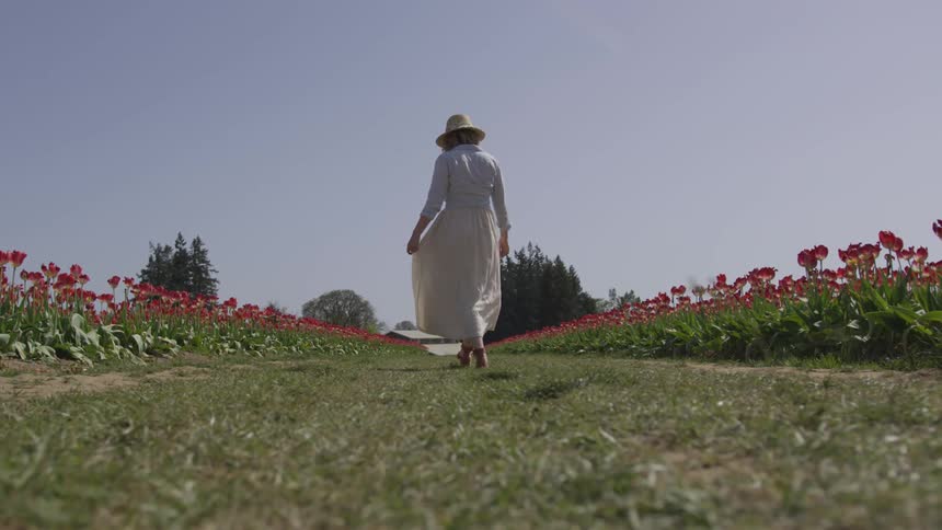Woman walks between rows of flowers