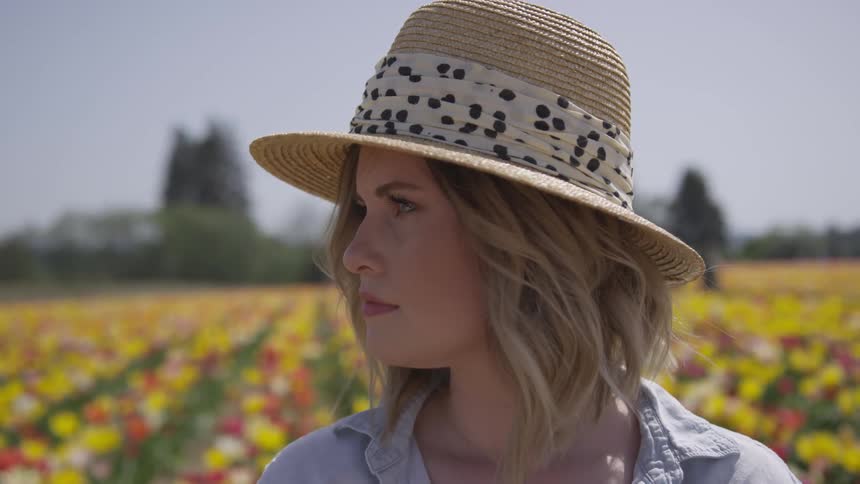 A woman is wearing a hat outdoors in a field