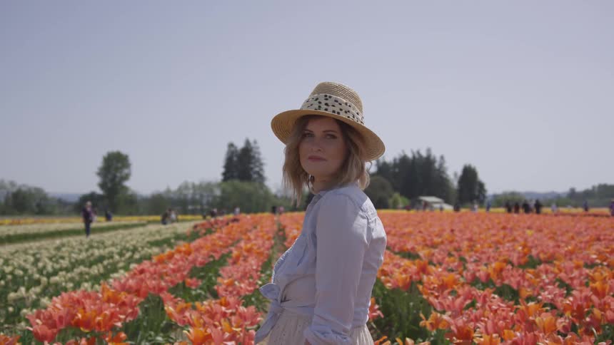 A woman stands in a field of flowers