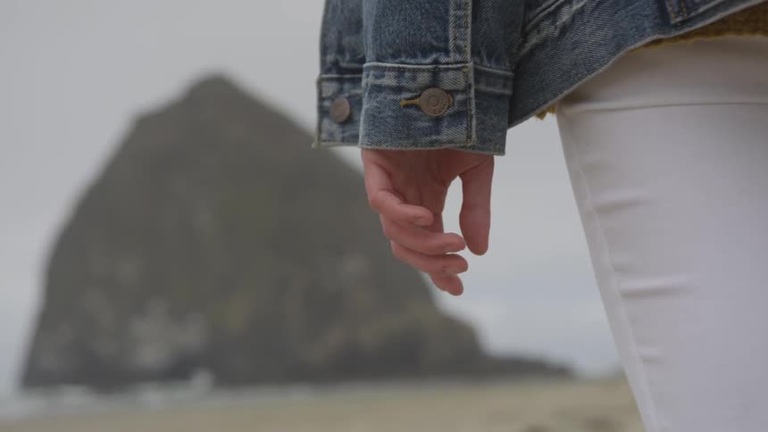A white woman standing on a beach during the day