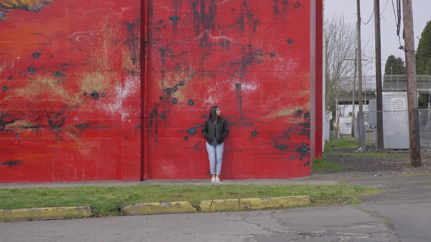 A woman standing in front of a red wall in a city