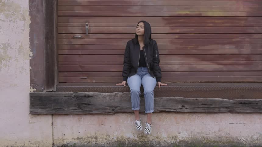 A woman sitting on a ledge in front of a large door