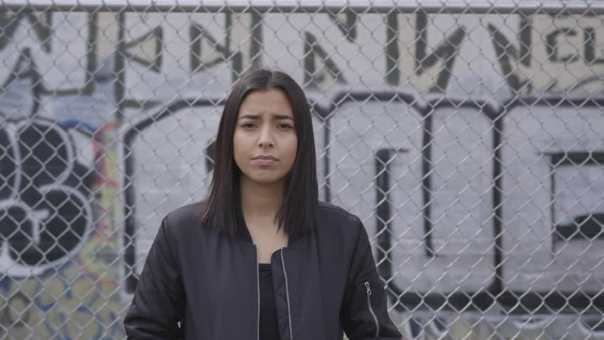 A woman is standing outside by graffiti