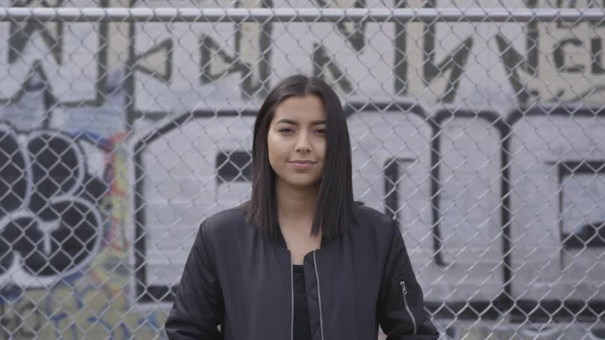 Woman leaning on a wired fence looks up to the camera