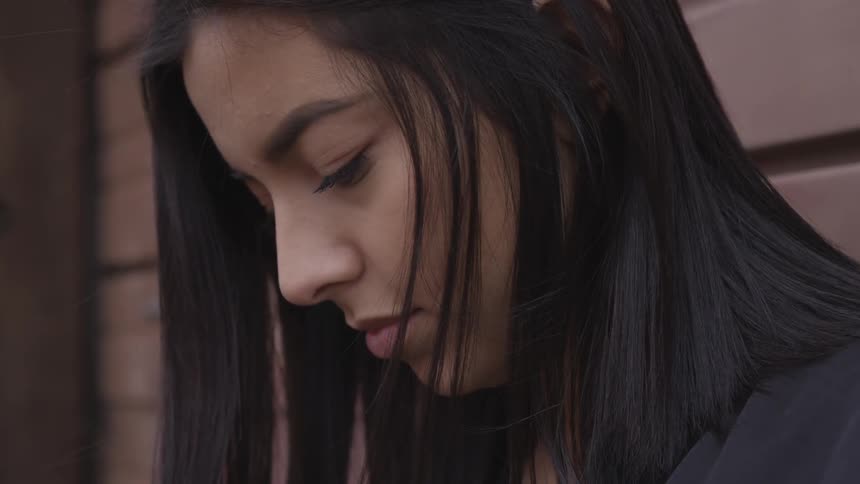 Young woman with dark hair looks down