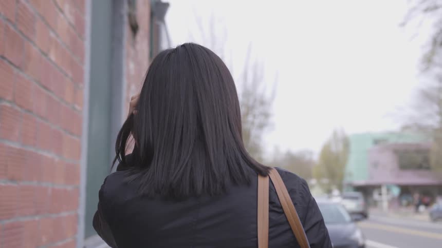 A woman walking down a sidewalk in a city