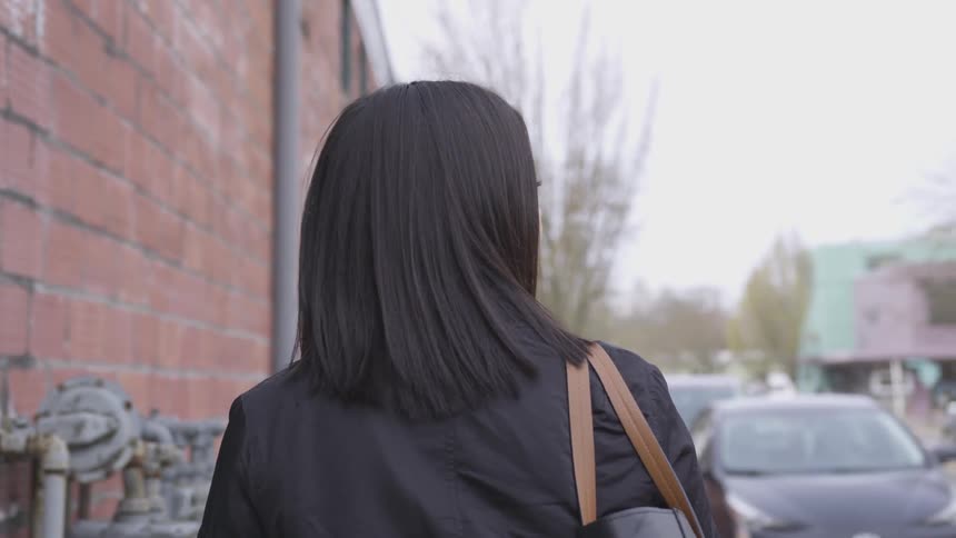 White woman walking on the sidewalk and looking to the right