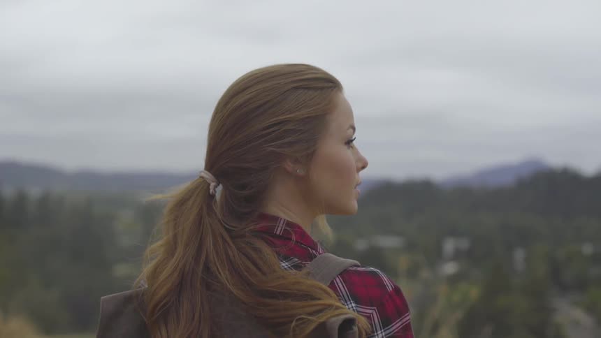 A young woman wearing a backpack looking out over the landscape below