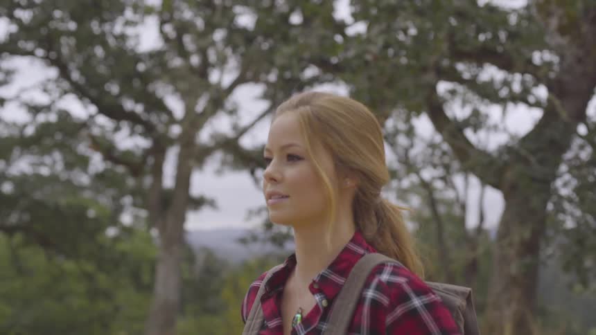 Woman looks up into trees while out on a hike