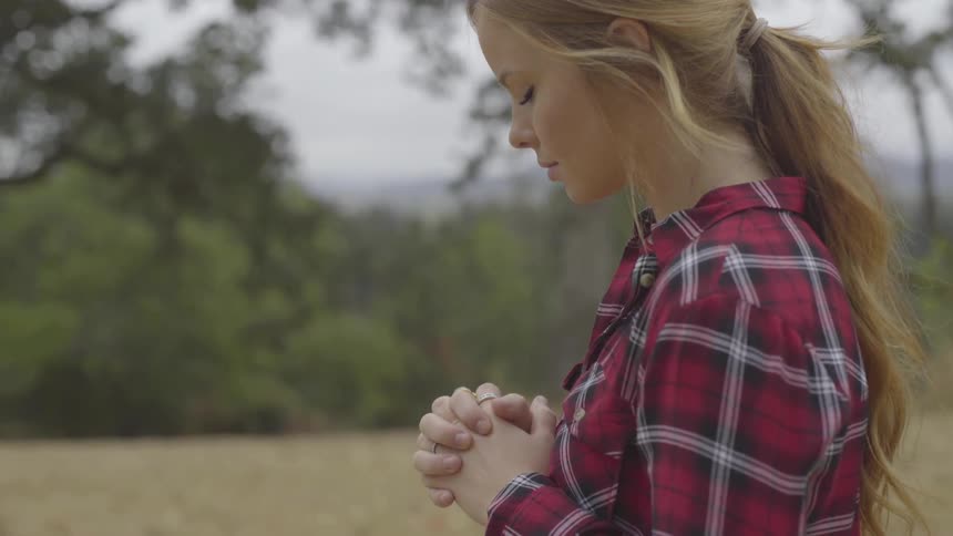 A woman praying in a wooded area