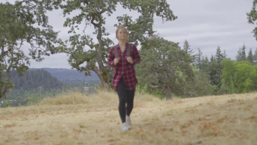 Woman hikes through green brush in forest