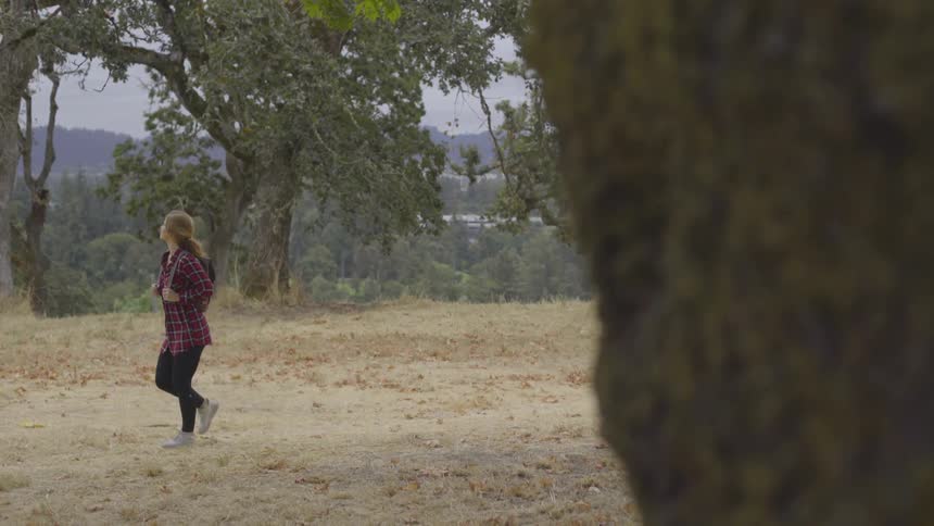 A woman hikes through a sparse wooded area in fall
