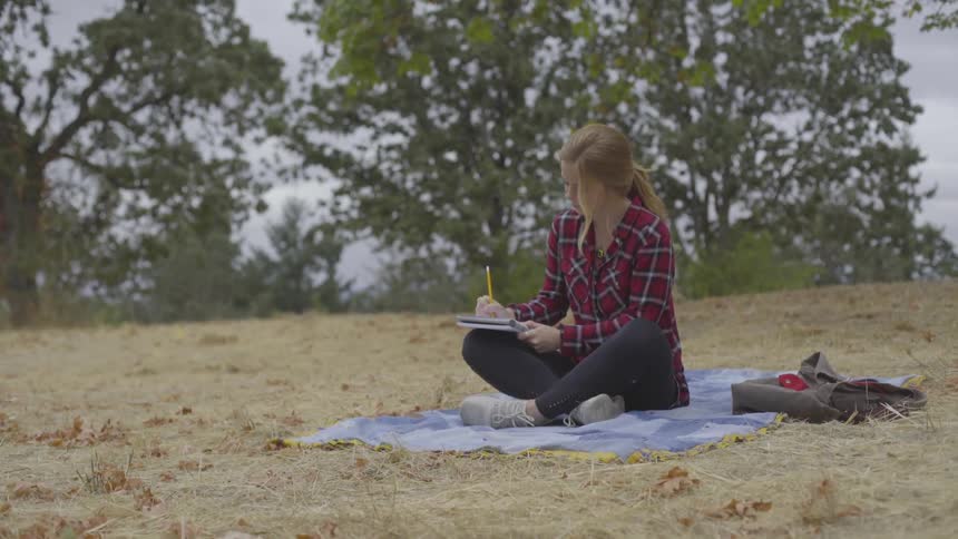 Girl writing in a notebook at the beach