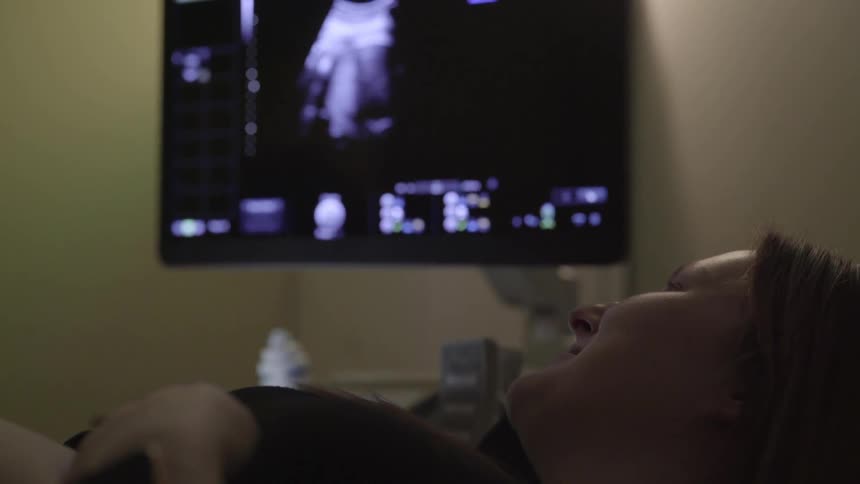 A woman laying in a hospital bed looking at a sonogram