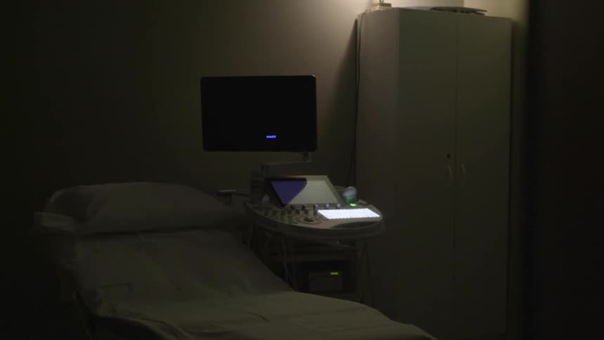 An empty exam room shows a bed and computer setup
