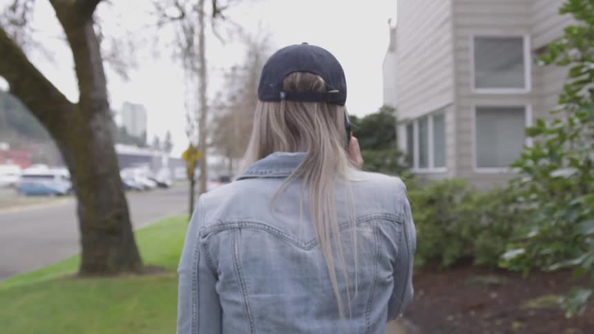 A woman on her phone walks down the sidewalk