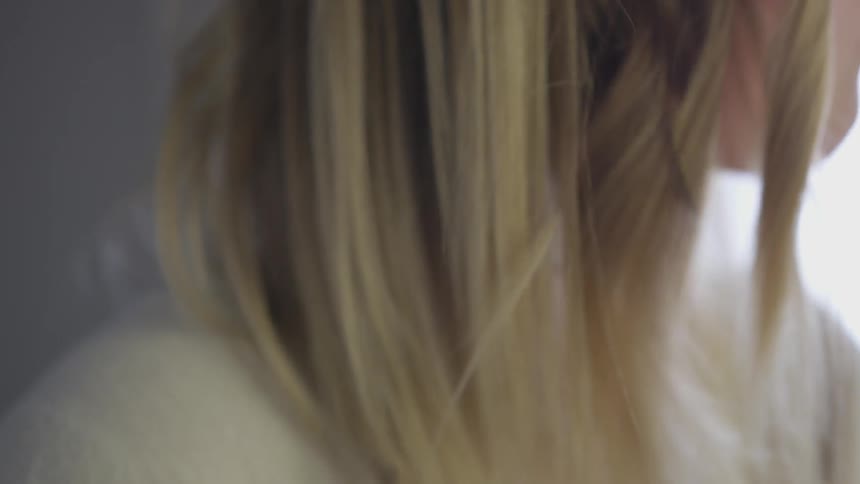 A woman curling her hair with a hot iron