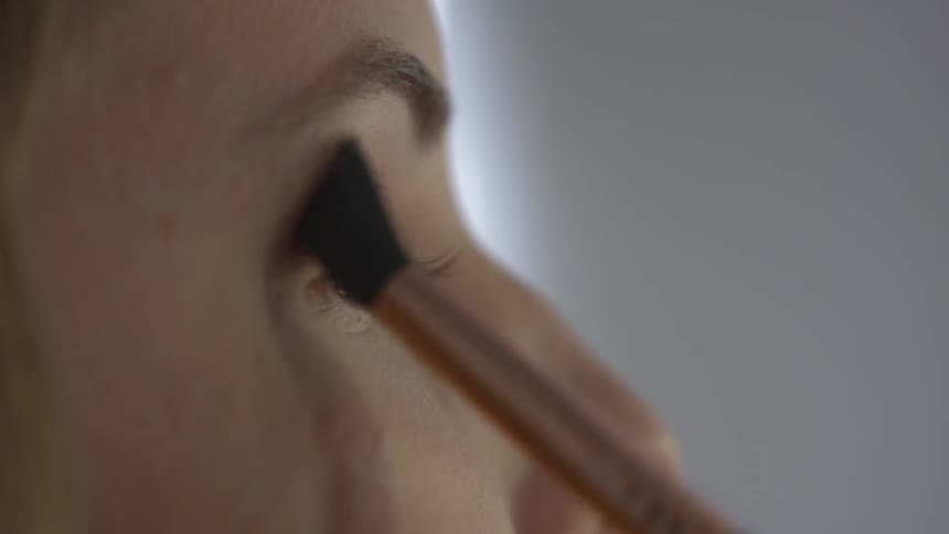 White woman applying eye shadow with a pencil