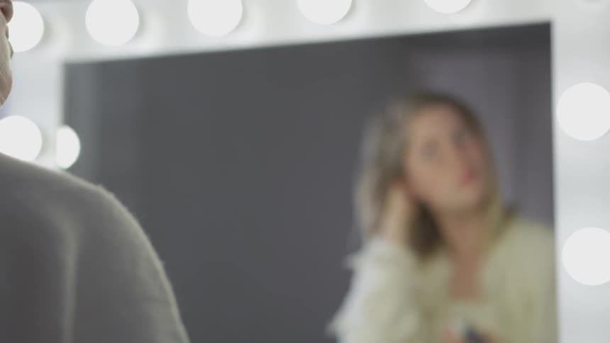 White woman fixing her hair in front of a mirror