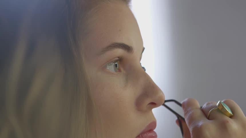 A woman is curling her eyelashes