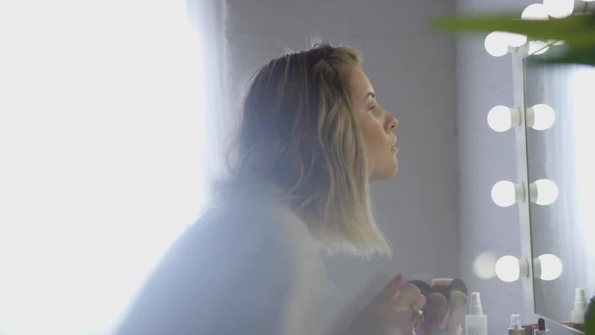 A woman putting on makeup in a mirror
