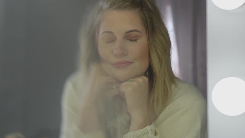 A woman resting her chin in her hands as she closes her eyes